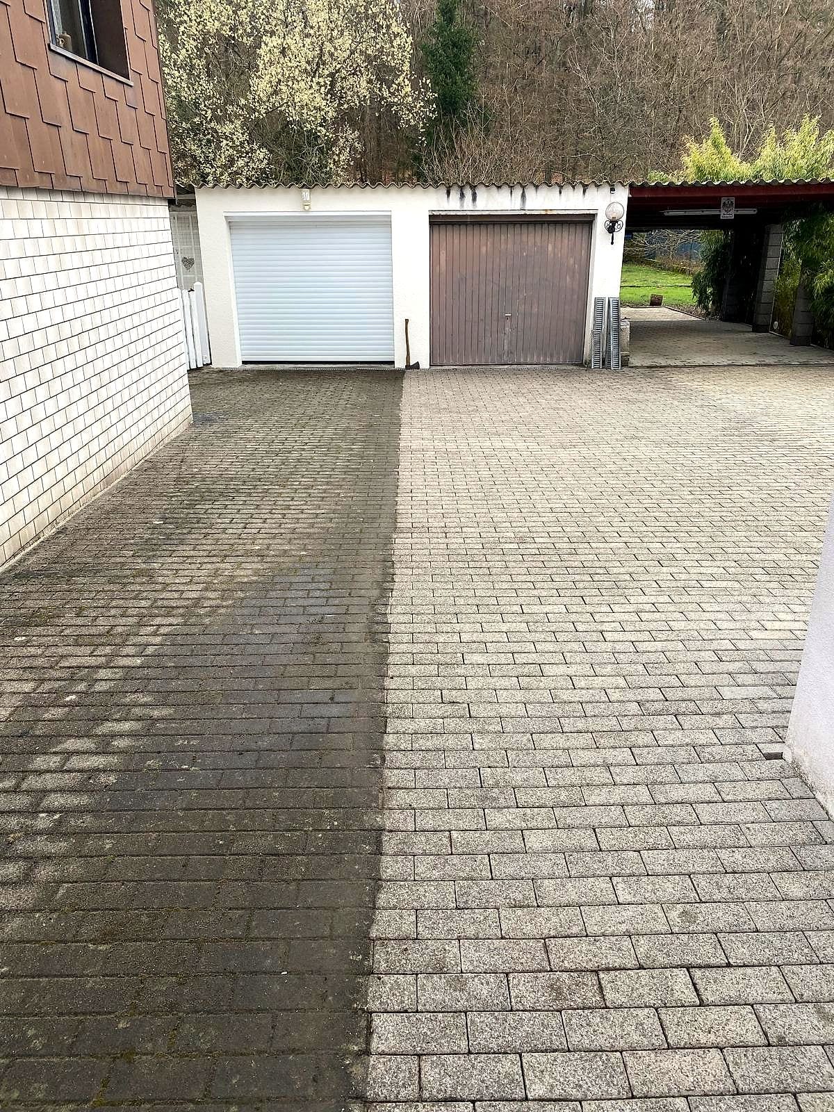 Einfahrt aus Betonpflaster während der Reinigung: links die noch vermooste Fläche, rechts der gereinigte Belag, dazwischen eine gerade Kante.