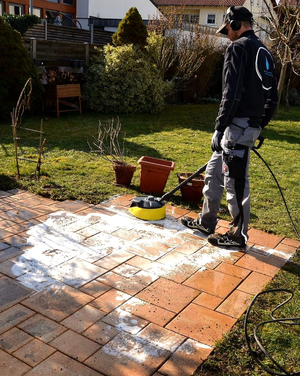 Terrassenfläche wird mit dem Flächenreiniger gereinigt; der gereinigte Streifen hebt sich deutlich vom noch ungereinigten Belag ab.